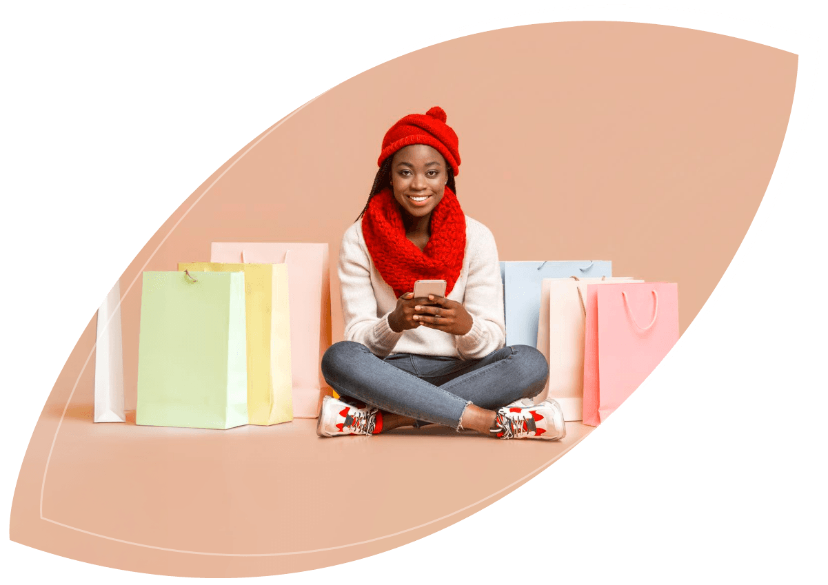 woman sitting holding phone in hand surrounded by shopping bags